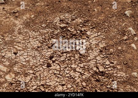 The arid terrain of Morocco displays cracked soil and scattered stones under a blazing sun, typical of hot, dry climates in North Africa. The beige la Stock Photo