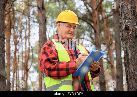 Senior forester taking notes on clipboard in forest Stock Photo