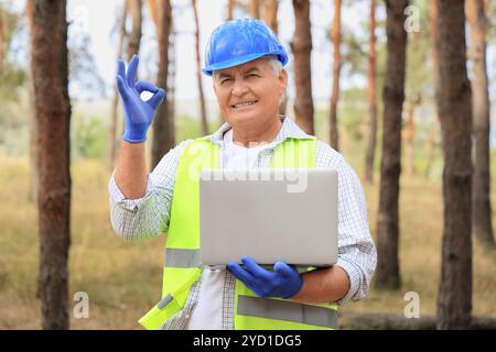 Senior forester with laptop showing OK in forest Stock Photo