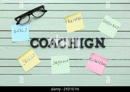 Word COACHING with sticky notes and eyeglasses on green wooden background Stock Photo
