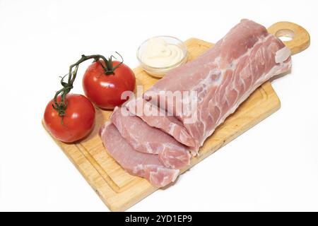 Pork chop isolated on white background. Meat on a white background. Raw meat and red tomatoes. Tomatoes on the branch. Stock Photo