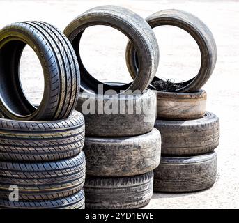 New and used car tires stacked up on asphalt road Stock Photo