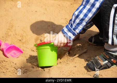 The boy plays in the sand in the sandbox. Children's games. Sandbox. Children's sand tins. Happy boy . Stock Photo