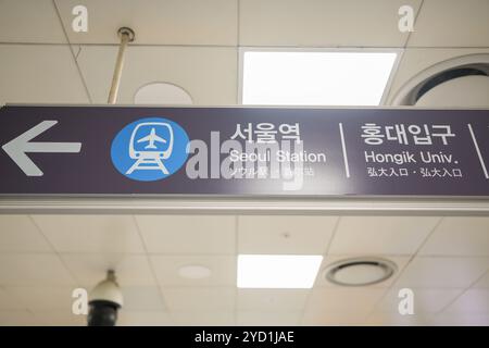 Sign with an arrow pointing to Seoul Station. The sign is in a foreign language. The sign is hanging from the ceiling Stock Photo