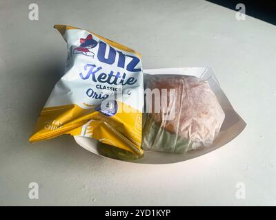 A lobster roll and Utz Kettle potato chips in a basket, wrapped and ready for eating. At Young's Lobster Pound at the harbor of Belfast, Maine, USA. Stock Photo