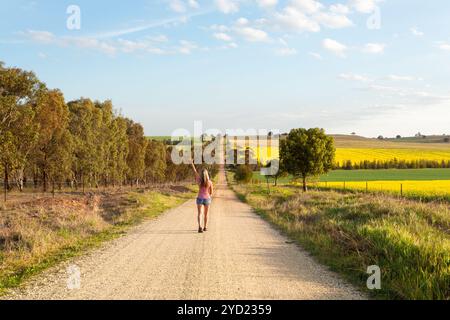 Woman walking along a dusty road among the rural fields Stock Photo