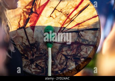 A close up view of a traditionally dyed colorful native drum and beater in the hands of a musician during a daytime music celebration. Stock Photo