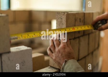 Man making measurements while working on his brick wall Stock Photo