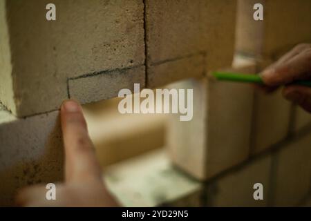 Man is measuring bricks while building a wall Stock Photo