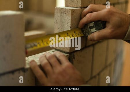 Man making measurements while working on his brick wall Stock Photo