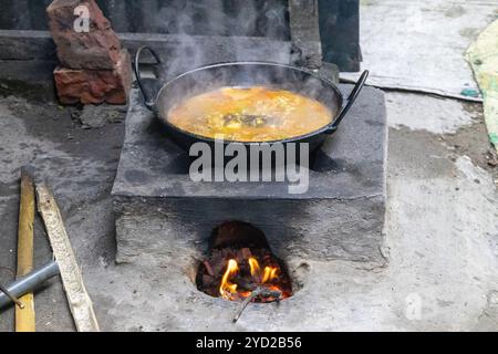 Fish curry cooking on a traditional mud stove. Village kitchen in Bangladesh. This stoves made of clay and fueled with wood, commonly used by resident Stock Photo