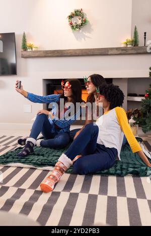 Mutliracial female friends taking selfie, enjoying christmas together, at home Stock Photo