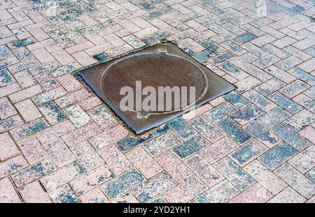 Rusty metal manhole cover on pavement road Stock Photo