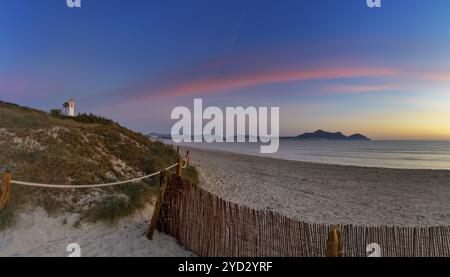 Picturesque Playa del Muro beach with sand dunes and a view of the historic maritime observation towers and the town of Alcudia in the background Stock Photo