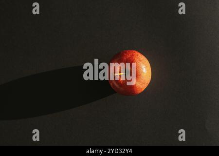 Red apple forming a shadow against black backround Stock Photo