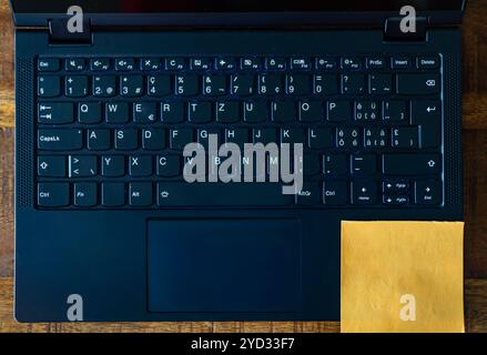 A laptop keyboard with a yellow sticky note on the bottom. Stock Photo