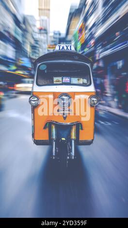 A Tuk-Tuk Taxi Racing Along A Busy Street In Bangkok Stock Photo