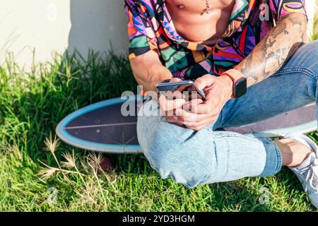 unrecognizable male sitting on skate using phone Stock Photo