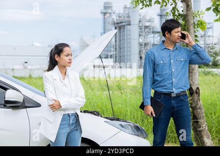 Women Car Broken on the Road. Young Couple Inspecting Car Engine on a Scenic Roadside Stock Photo
