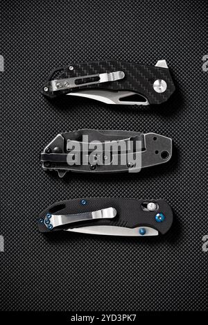 Closed three folding knifes on black background. EDC for men concept. Stock Photo