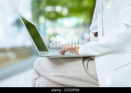 Closeup business people hand typing at laptop computer keyboard. Businesswomen outdoor working at green city background. Stock Photo