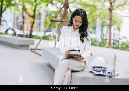 Smart young engineer using tablet sketch design at green park nature. Environmental saving energy project designer working women . Stock Photo