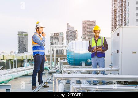 Team of HVAC engineer working in boiler rooftop, Engineer working in gas pipe boiler steam of factory industrial building. working in the boiler pipin Stock Photo