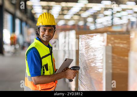 Portrait Happy Indian male worker inventory barcode check. Warehouse staff in safety work in factory cargo warehouse. Stock Photo