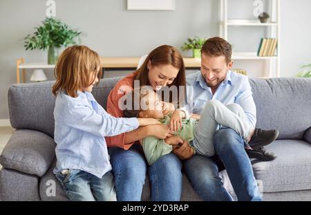 Family fun, cheerful excited parents tickling beloved kid girl, playing with child at home laughing  Stock Photo