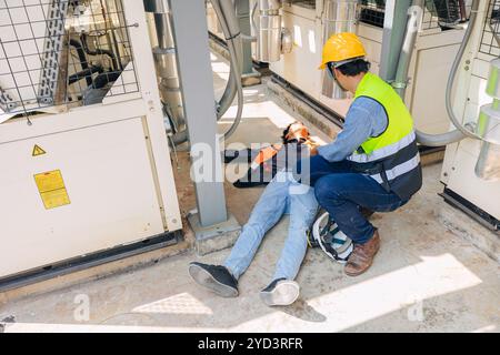 Worker emergency help colleague down injury at industrial site, accident at work safety. Stock Photo