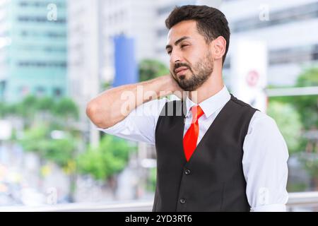Hispanic indian business man muscle join neck pain from office syndrome after hard working day. Stock Photo