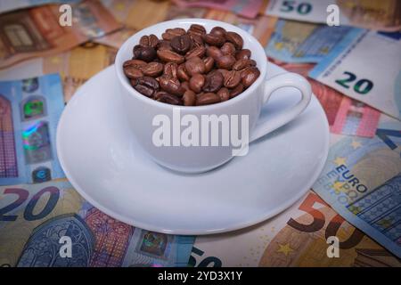 Espressotasse gefüllt mit Kaffeebohnen auf Euro Geldscheinen *** Espresso cup filled with coffee beans on euro banknotes Nordrhein-Westfalen Deutschland, Germany GMS17924 Stock Photo