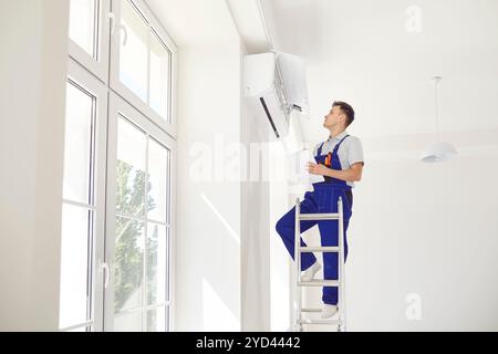 Worker Inspecting And Repairing Air Conditioner At Home Stock Photo