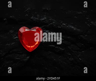 Red glass heart on a black textured surface. Stock Photo