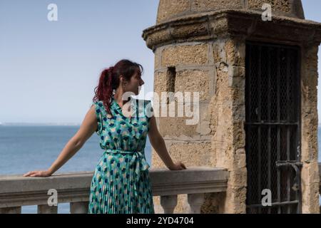 Redhead woman leaning on a railing with the sea in the background Stock Photo