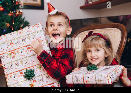 Brother and sister in Christmas outfits holding gifts in hands Stock Photo