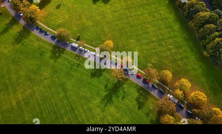Aerial view of a road winding along a green lake at the base of a lush ...