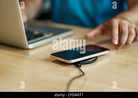 Smartphone with wireless fast charger pad, digital device gadget. Stock Photo