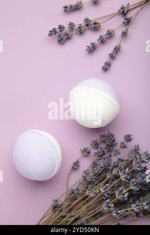 Natural cosmetics. Handmade lavender bath bombs and lavender flowers on purple background. Vertical photo. Stock Photo
