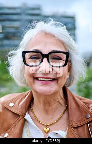 Close up portrait of attractive Caucasian mature woman posing in front of garden city area Stock Photo