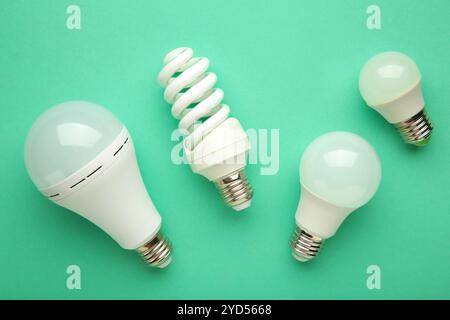 Comparison of different light bulbs on mint background. Top view Stock Photo