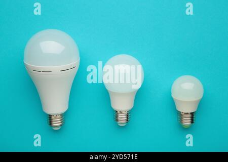 Comparison of different light bulbs on blue background. Top view Stock Photo
