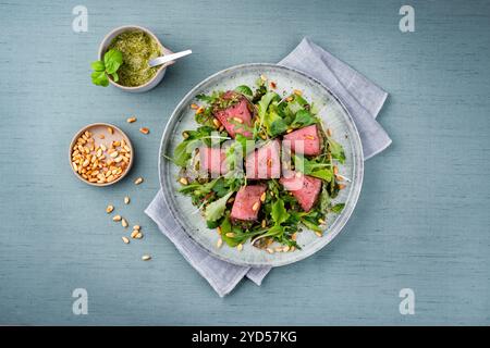 Traditional mixed salad with spinach filled roast beef rolls and pine nuts served as top view on a design plate with text space Stock Photo