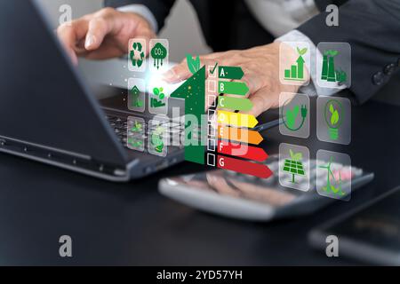 Energy efficiency concept. Businessman using laptop with energy efficiency rating symbol on virtual screen for energy efficient house building rate la Stock Photo