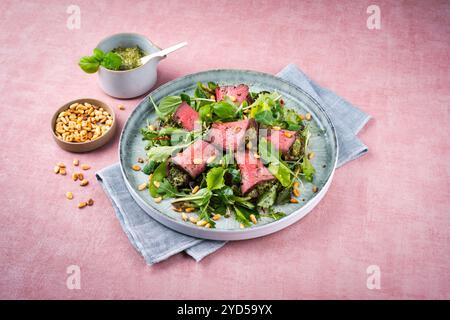 Traditional mixed salad with spinach filled roast beef rolls and pine nuts served as a close-up on a design plate with text spac Stock Photo