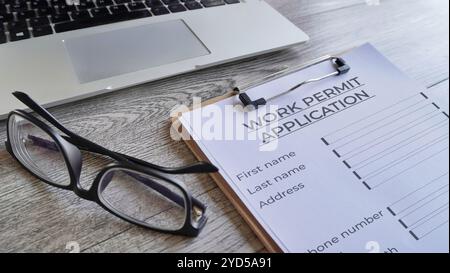 Closeup image of paper clipboard  with Work Permit Application form on wooden table. Stock Photo