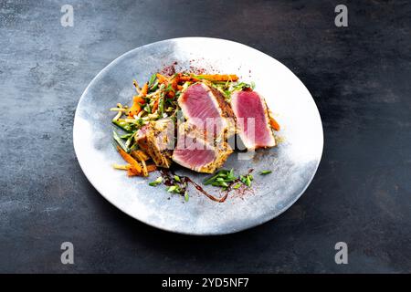 Traditional Japanese gourmet tuna fish steak tataki with vegetable slices and soy sprouts with sweet dour sauce served as close- Stock Photo