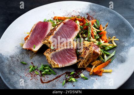 Traditional Japanese gourmet tuna fish steak tataki with vegetable slices and soy sprouts with sweet dour sauce served as close- Stock Photo