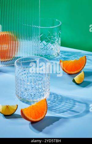 Two empty glass glasses on colored backgrounds with shadows from sunlight Stock Photo