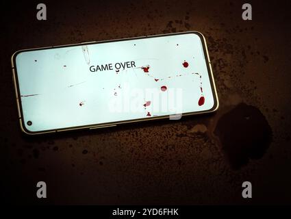 Image of game over words inscription on phone screen bloodstains splashes and spots background horror mood Stock Photo